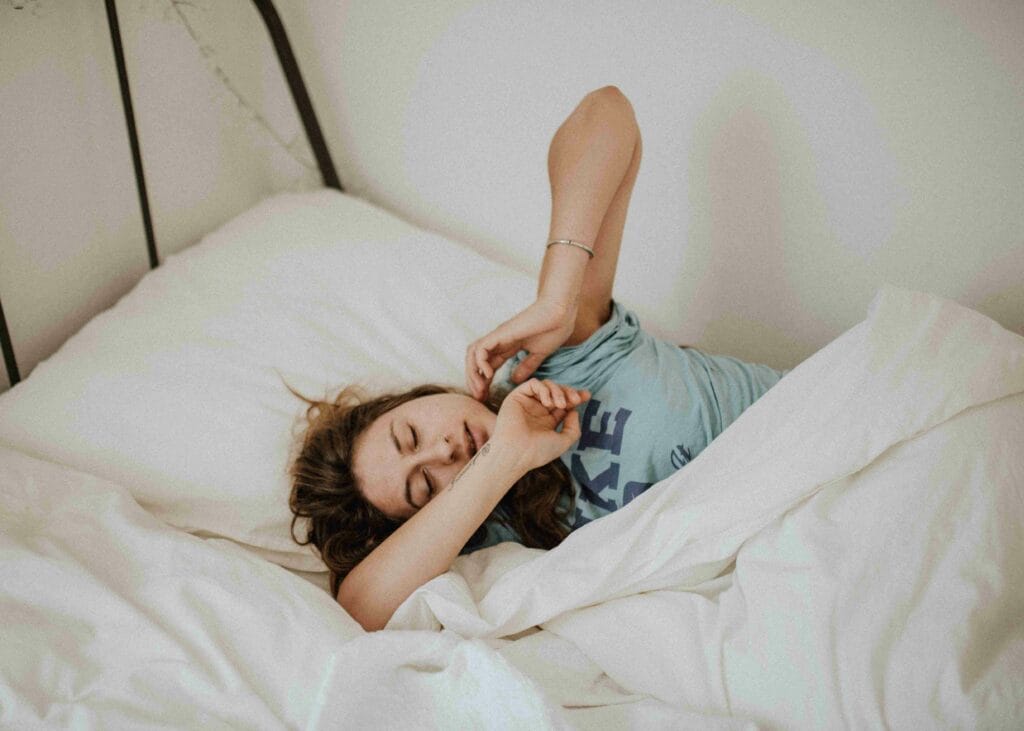 Eine Frau welche schläfrig auf dem Bett liegt wegen Cannbigerol Nebenwirkungen