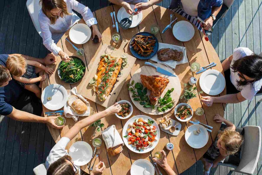 Plusieurs personnes lors d'un repas convivial avec une table remplie d'assiettes avec de la nourriture colorée