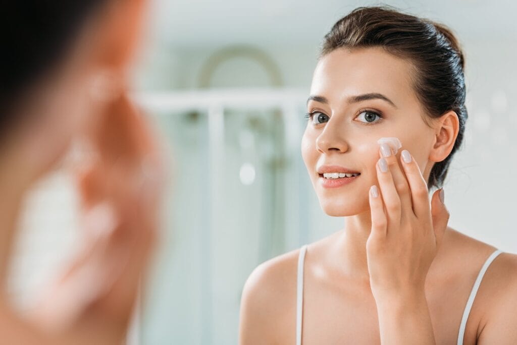Une femme s'appliquant une crème sur le visage pour symboliser les effets du CBD sur la peau