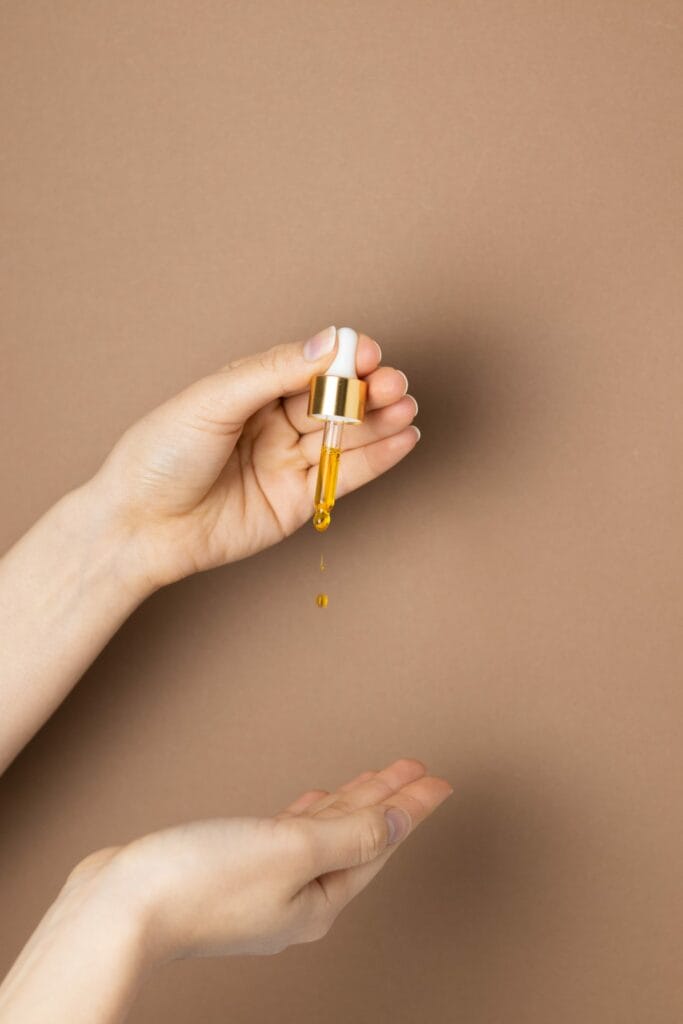 Une pipette pleine d'huile de chanvre dorée tombe doucement sur une main