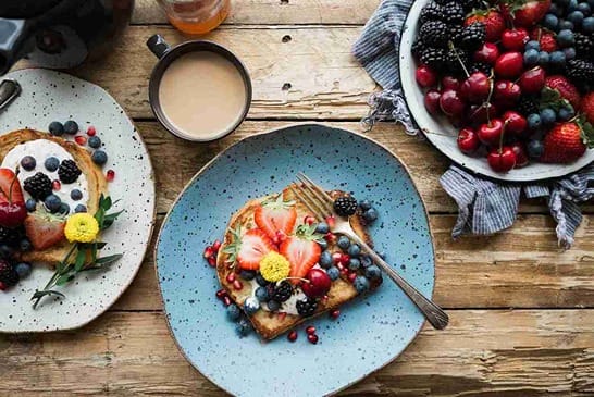 Auf zwei Tellern befindet sich ein Toast mit Früchten, auf dem dritten Teller sind nur Früchte zu sehen