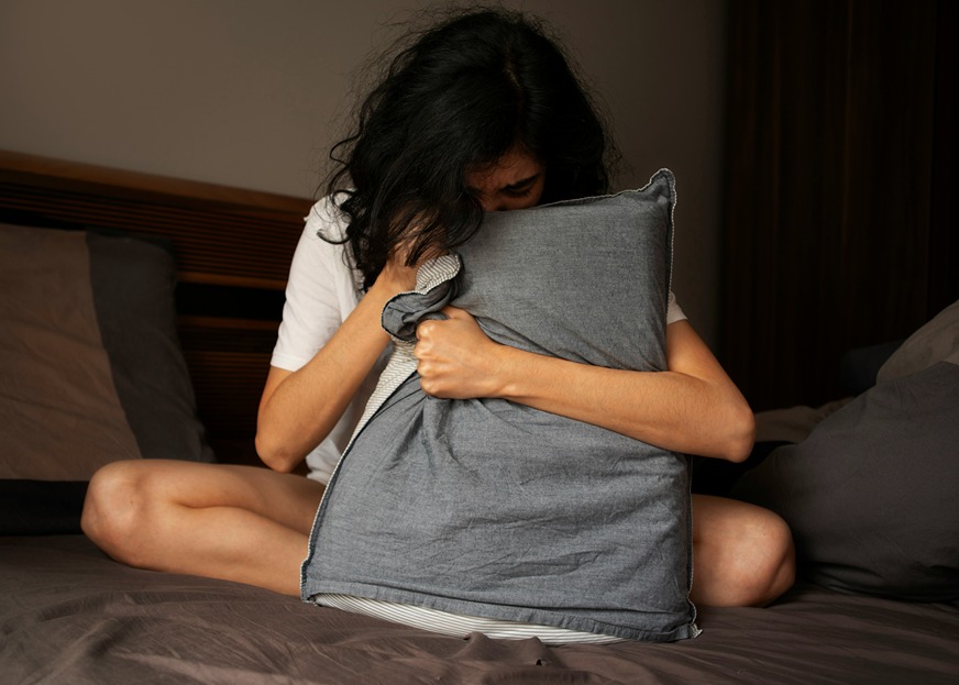 Femme anxieuse serrant un oreiller, illustrant les risques d’interactions du CBD avec les antidépresseurs